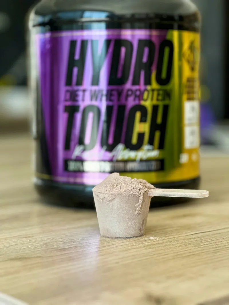 Protein powder jar and spoon on a table - mass gainer supplement